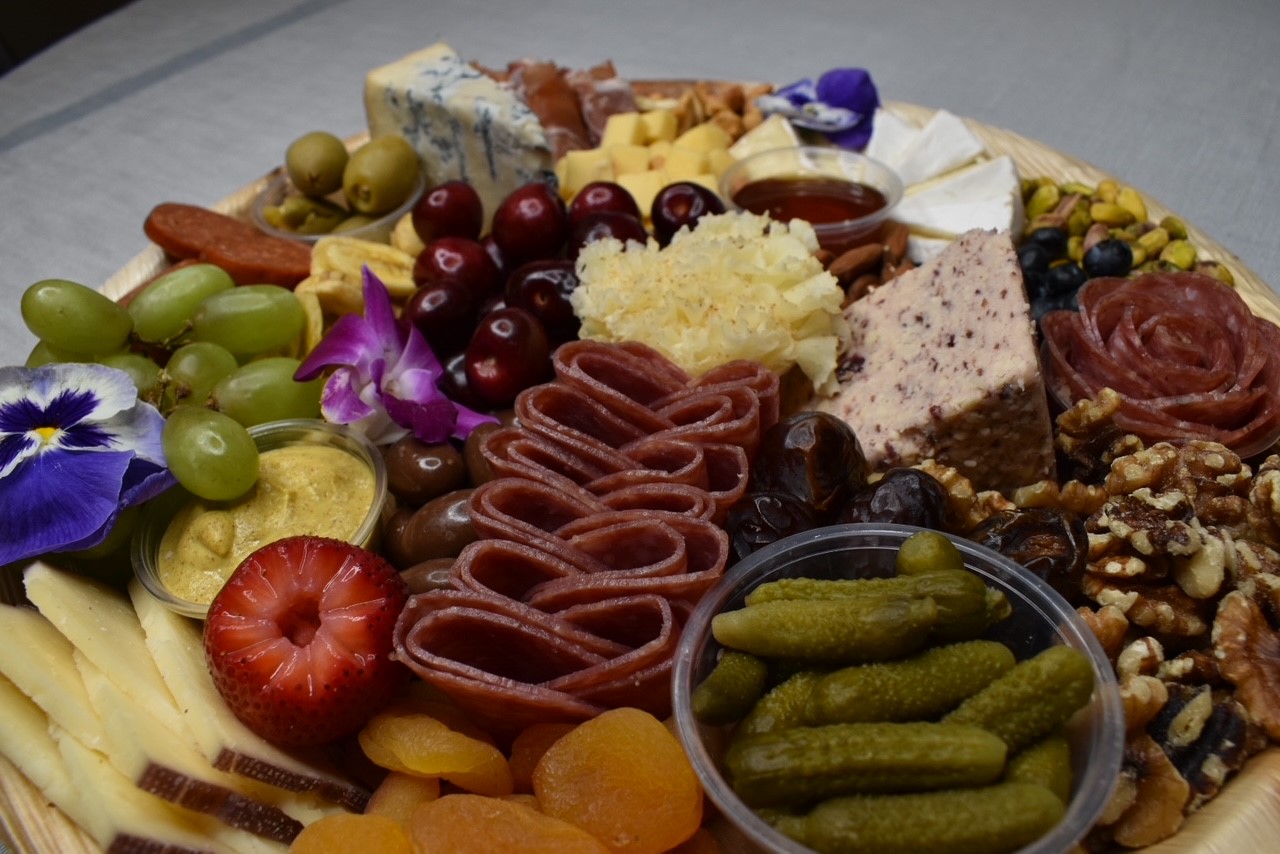Charcuterie board with blue cheese, grapes, orchids, and cured meats